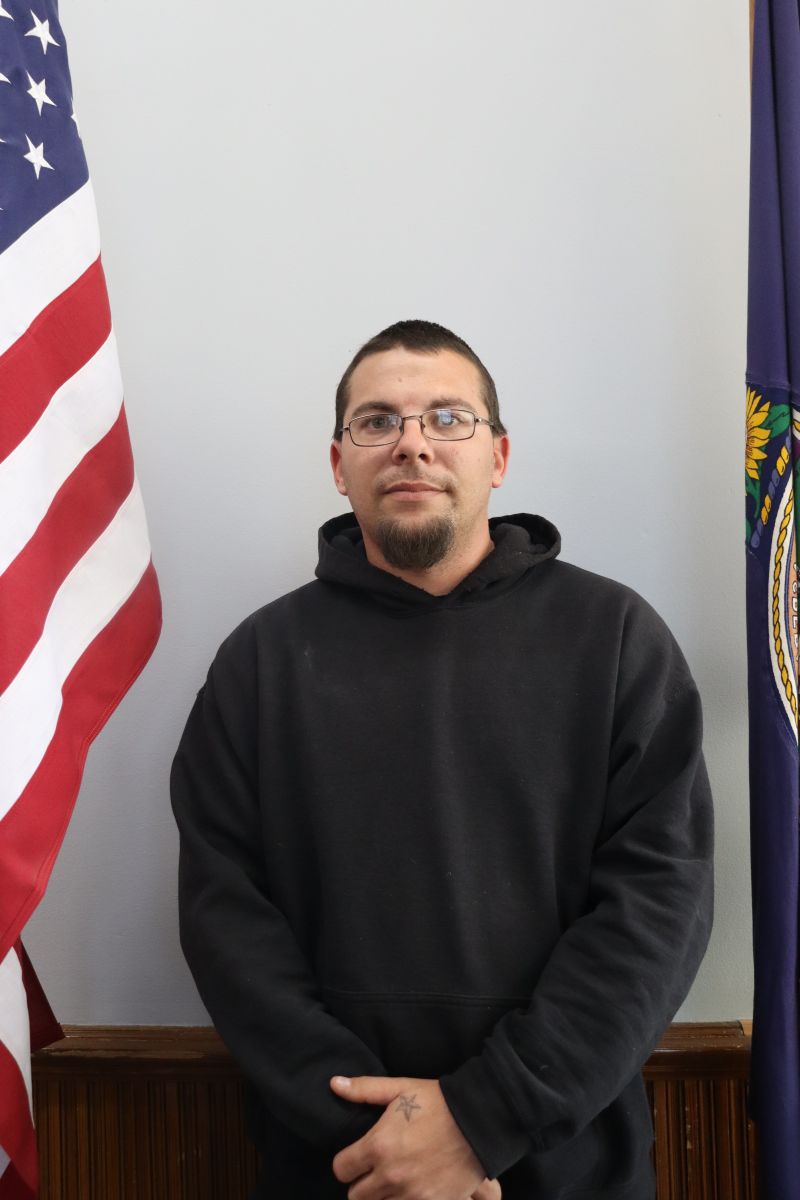 Photo of Maintenance Worker Travis Tipping in front of American and Kansas flag